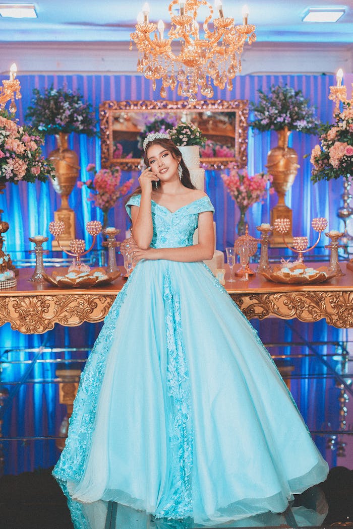 Stunning quinceañera with a light blue dress amidst luxurious decorations and floral arrangements.